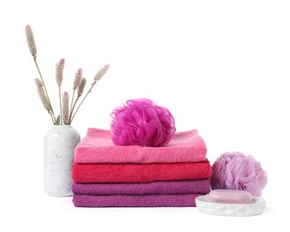 Photo of Stack of fresh terry towels, cosmetic products, sponges and floral decor isolated on white