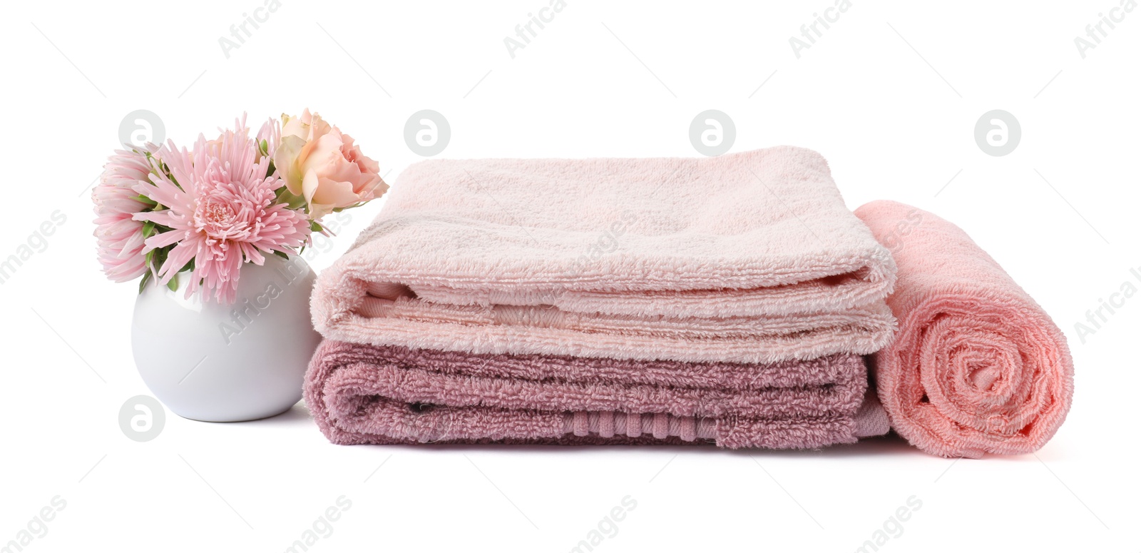 Photo of Stack of fresh terry towels and flowers isolated on white