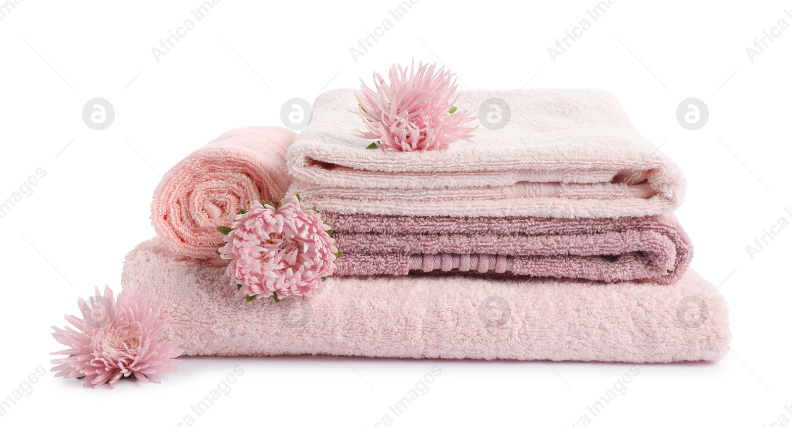 Photo of Stack of fresh terry towels and flowers isolated on white