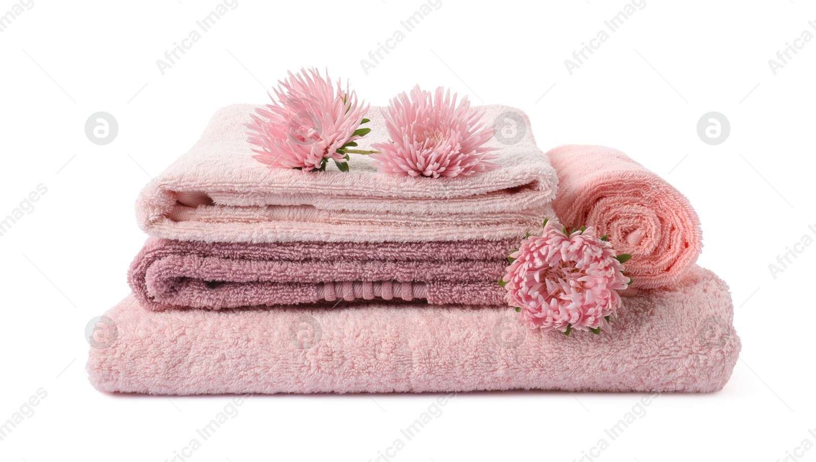 Photo of Stack of fresh terry towels and flowers isolated on white