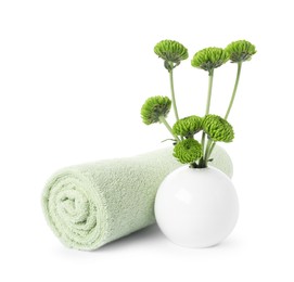 Photo of Rolled terry towel and green flowers isolated on white