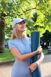 Photo of Happy young woman with yoga mat outdoors