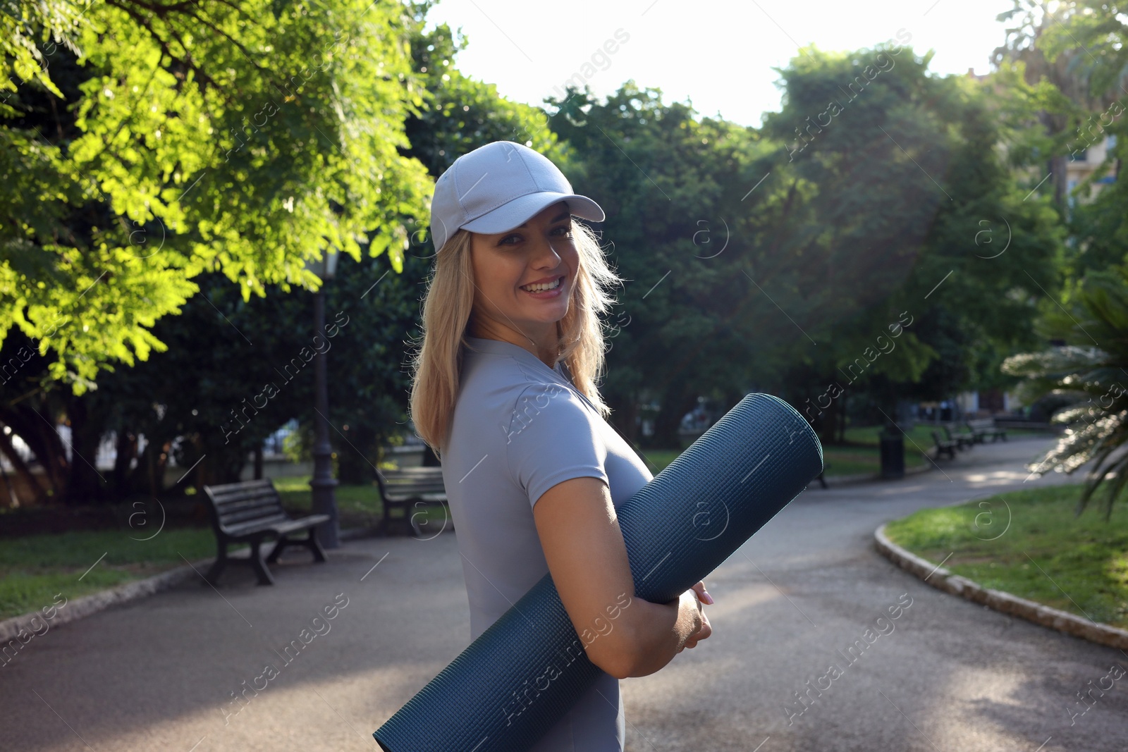 Photo of Happy young woman with yoga mat outdoors