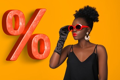 Image of Woman in stylish sunglasses and percent sign on orange background