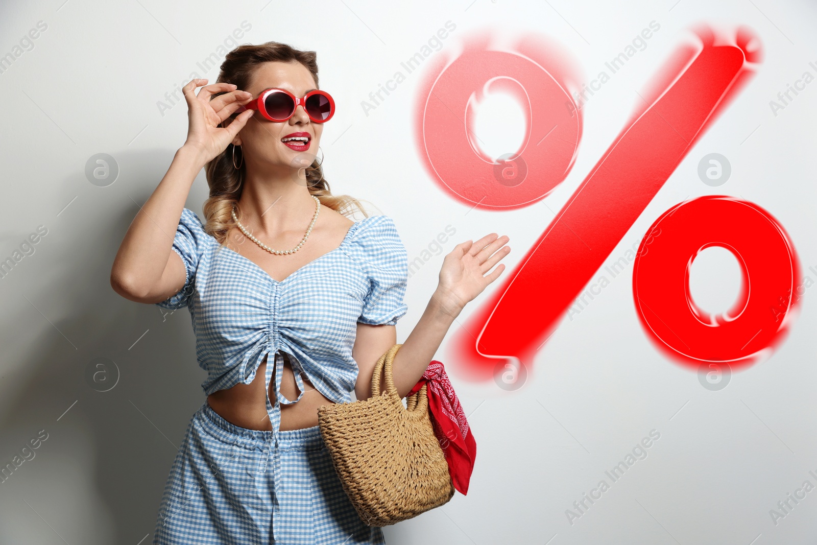 Image of Fashionable woman with bag looking at red percent sign against white background