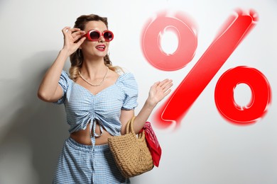 Image of Fashionable woman with bag looking at red percent sign against white background