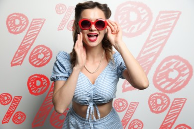 Image of Amused woman against light background with drawn red percent signs