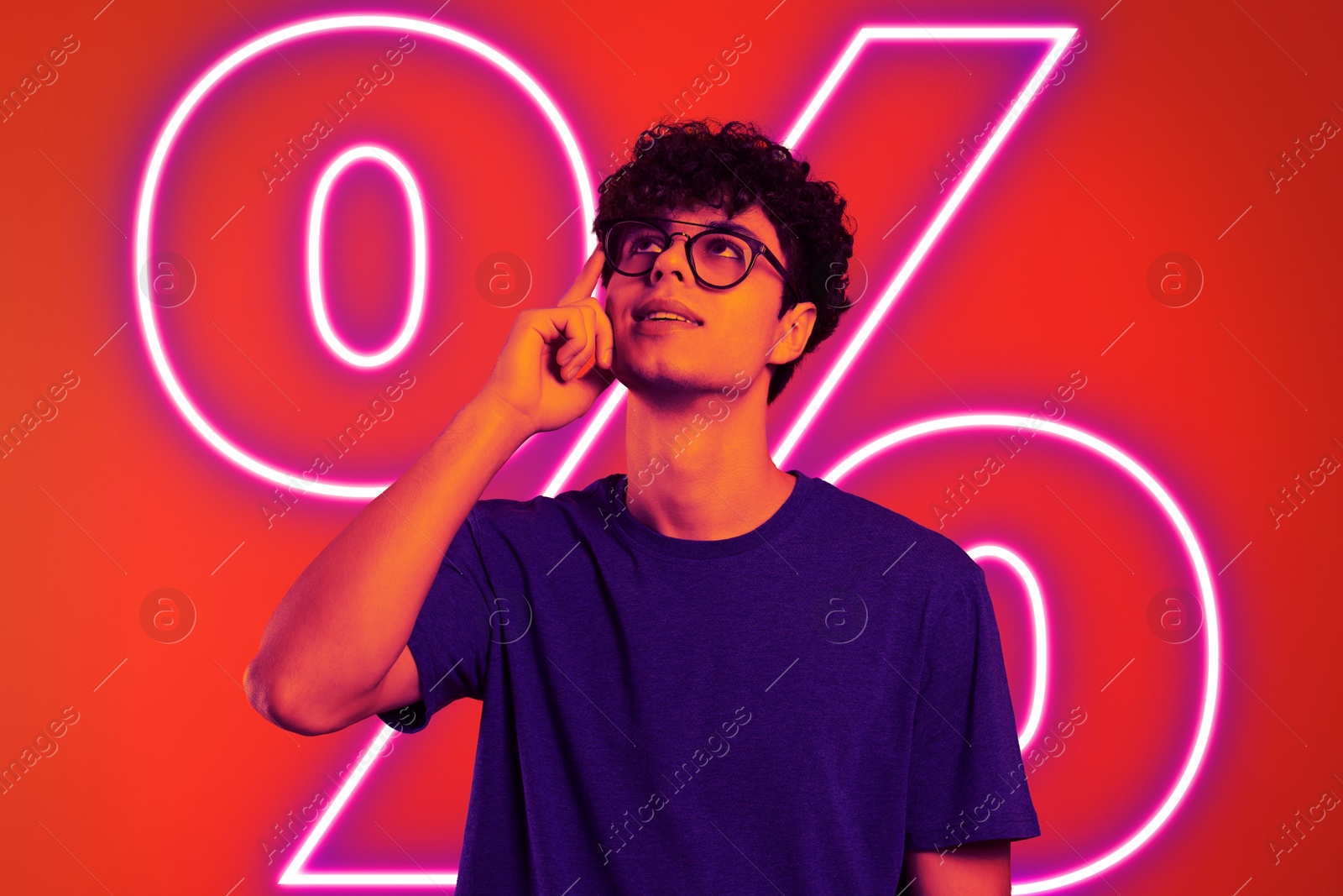 Image of Man in neon light against red background with glowing percent sign