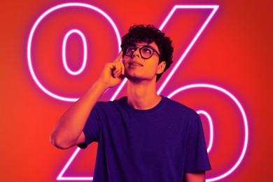 Image of Man in neon light against red background with glowing percent sign