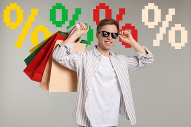 Image of Happy man with shopping bags against grey background with percent signs