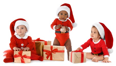 Image of Adorable babies with Santa hats and gift boxes on white background. Christmas celebration