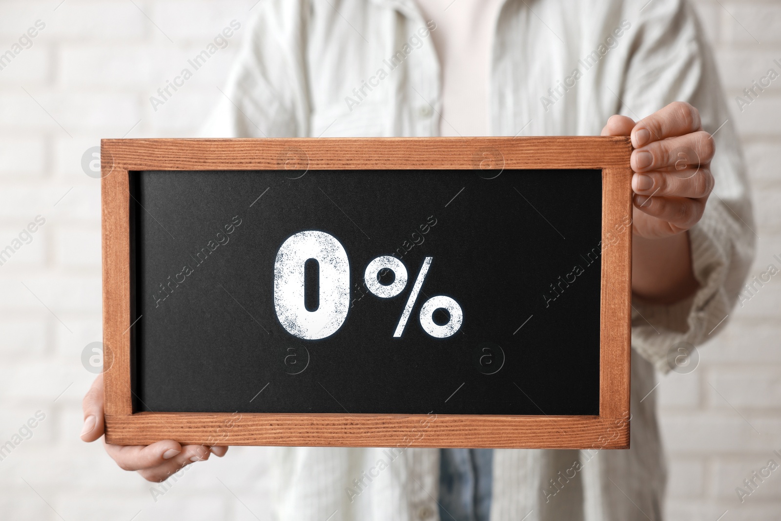 Image of Zero percent commission. Woman holding chalkboard with 0% indoors, closeup
