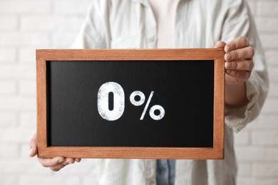 Image of Zero percent commission. Woman holding chalkboard with 0% indoors, closeup