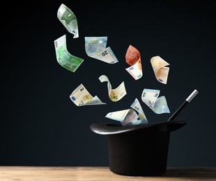 Image of Money flying out of magician's hat against black background