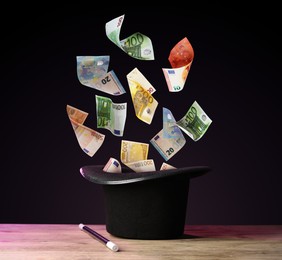 Image of Money flying out of magician's hat against black background
