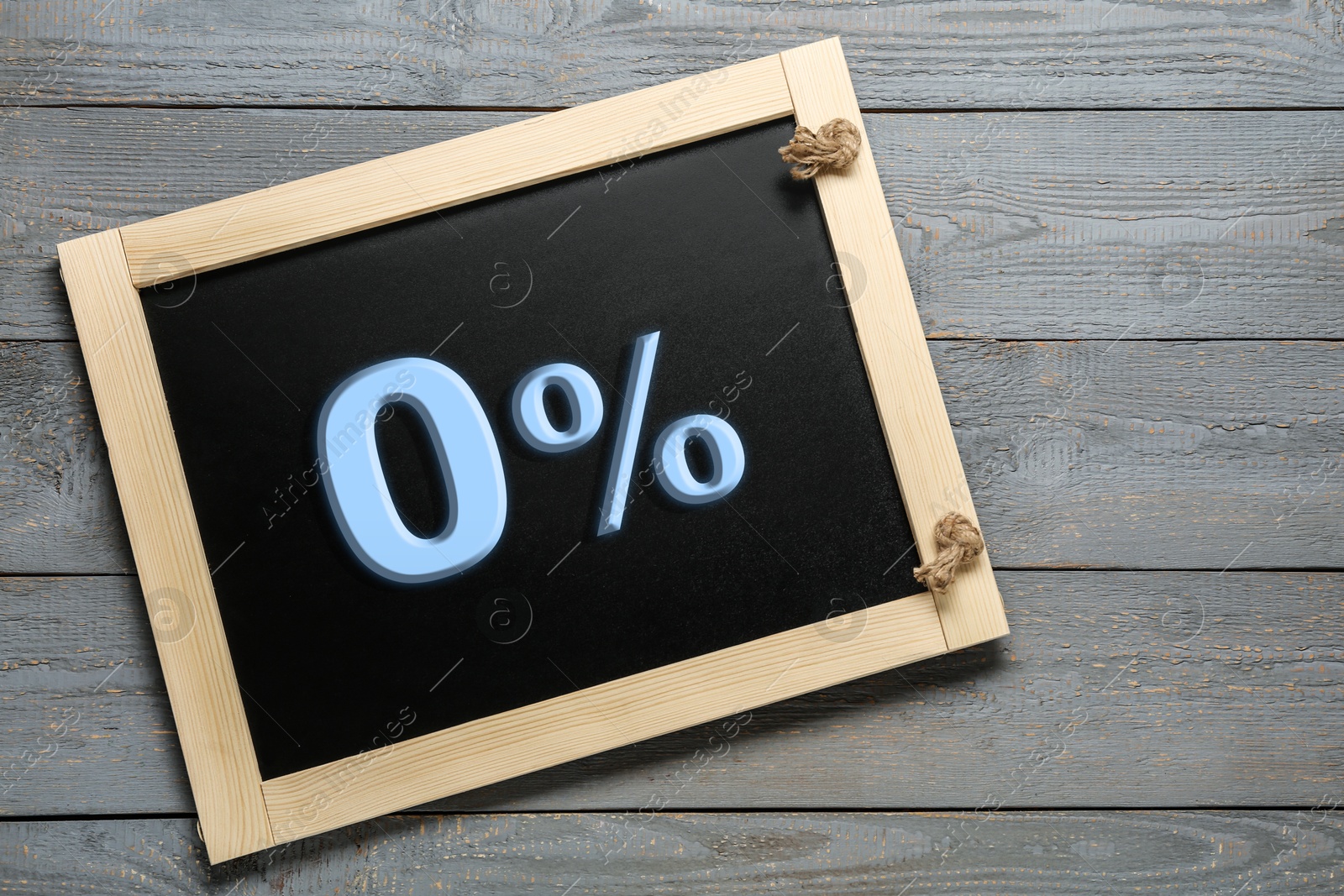 Image of Zero percent commission. Chalkboard with 0% on grey wooden background, top view