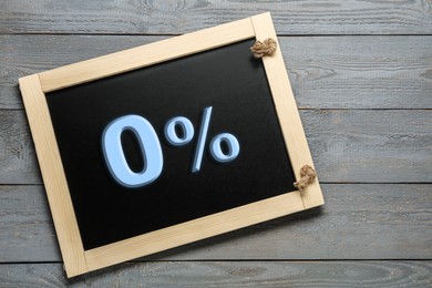 Image of Zero percent commission. Chalkboard with 0% on grey wooden background, top view