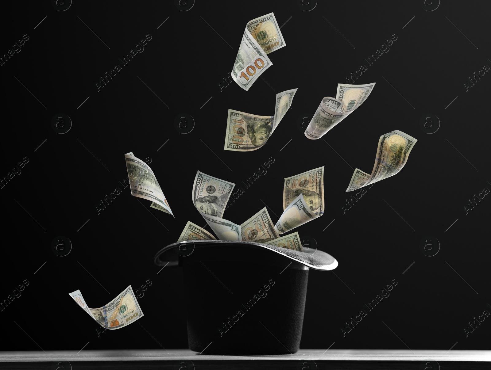 Image of Money flying out of magician's hat against black background