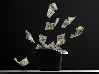 Image of Money flying out of magician's hat against black background