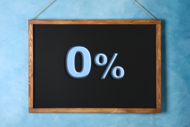 Image of Zero percent commission. Chalkboard with 0% hanging on light blue wall