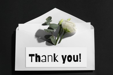 Image of Thank card and flower in envelope on black background, top view
