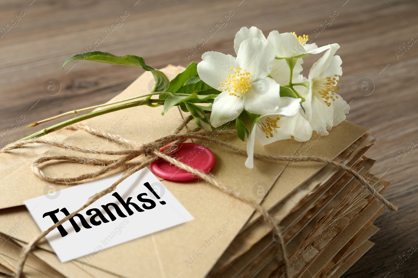 Image of Thank tag, flowers and stack of letters on wooden table, closeup