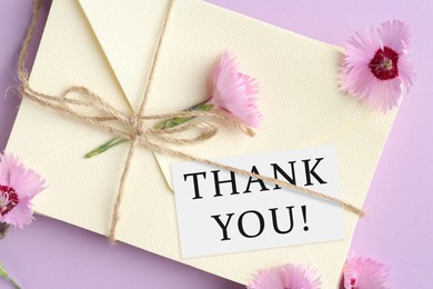 Image of Thank tag, flowers and stack of letters on violet background, top view