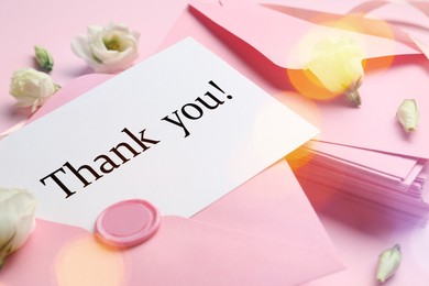 Image of Thank card, flowers and letters on pink background, closeup. Bokeh effect