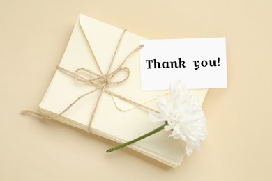 Image of Thank tag, flower and stack of letters on beige background, top view