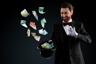 Image of Magician performing trick with money flying out of hat against black background