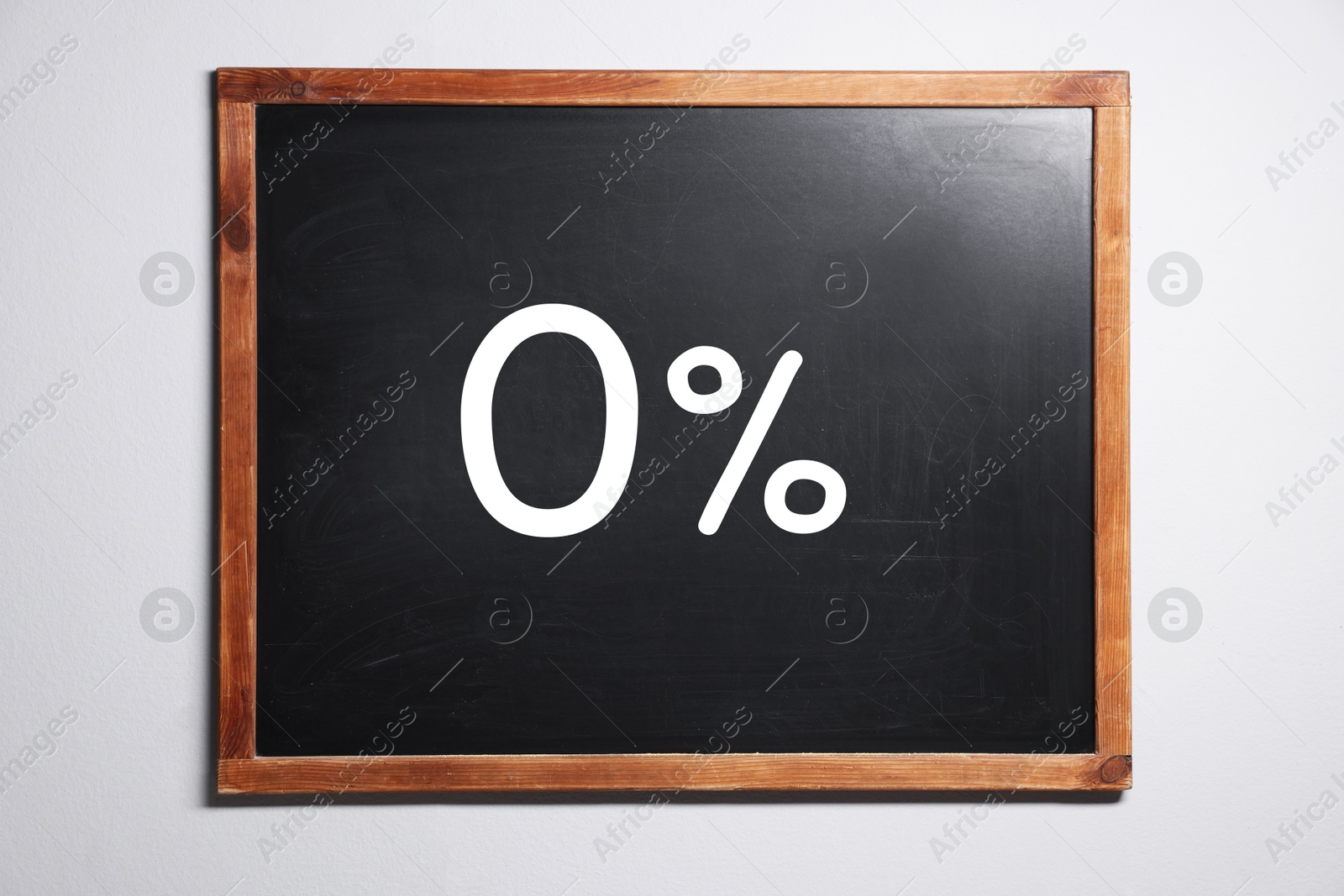 Image of Zero percent commission. Chalkboard with 0% hanging on white wall