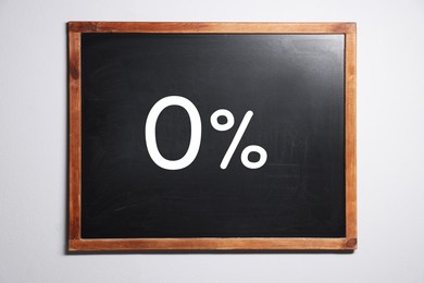 Image of Zero percent commission. Chalkboard with 0% hanging on white wall