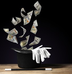 Image of Money flying out of magician's hat against black background
