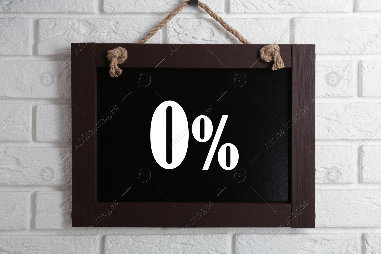 Image of Zero percent commission. Chalkboard with 0% hanging on white brick wall