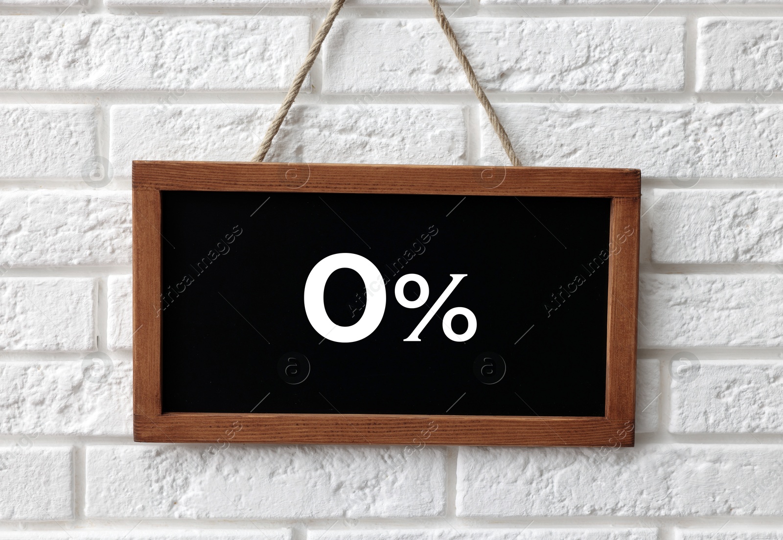 Image of Zero percent commission. Chalkboard with 0% hanging on white brick wall