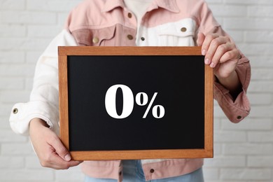 Image of Zero percent commission. Woman holding chalkboard with 0% indoors, closeup