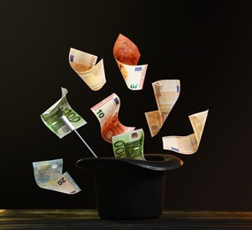 Image of Money flying out of magician's hat against black background