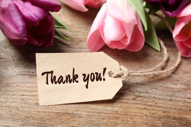 Image of Thank tag and tulip flowers on wooden table