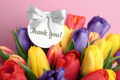 Image of Thank tag and bouquet of tulips against pink background