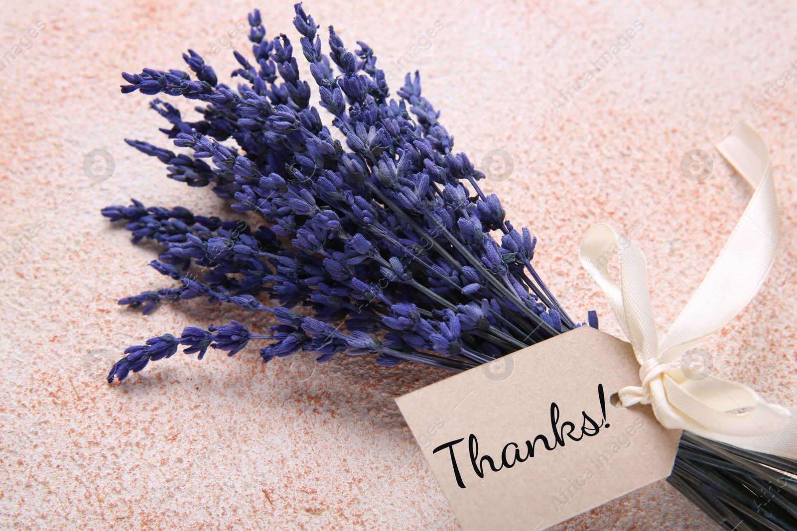 Image of Thank tag attached to bouquet of lavender flowers on textured background, closeup