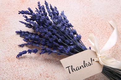 Image of Thank tag attached to bouquet of lavender flowers on textured background, closeup