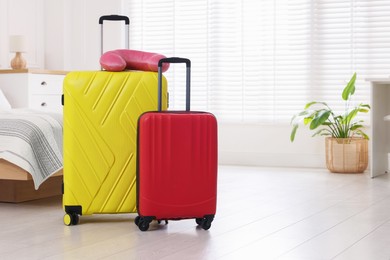 Photo of Stylish suitcases and travel pillow on floor indoors, space for text