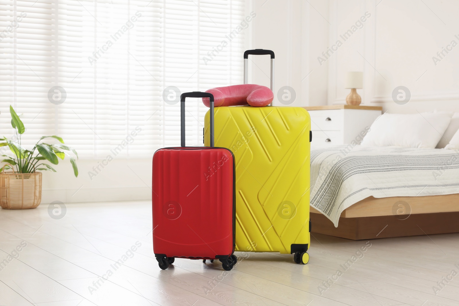 Photo of Stylish suitcases and travel pillow on floor indoors