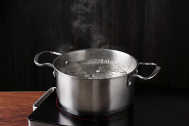 Photo of Metal pot with boiling water on stove in kitchen