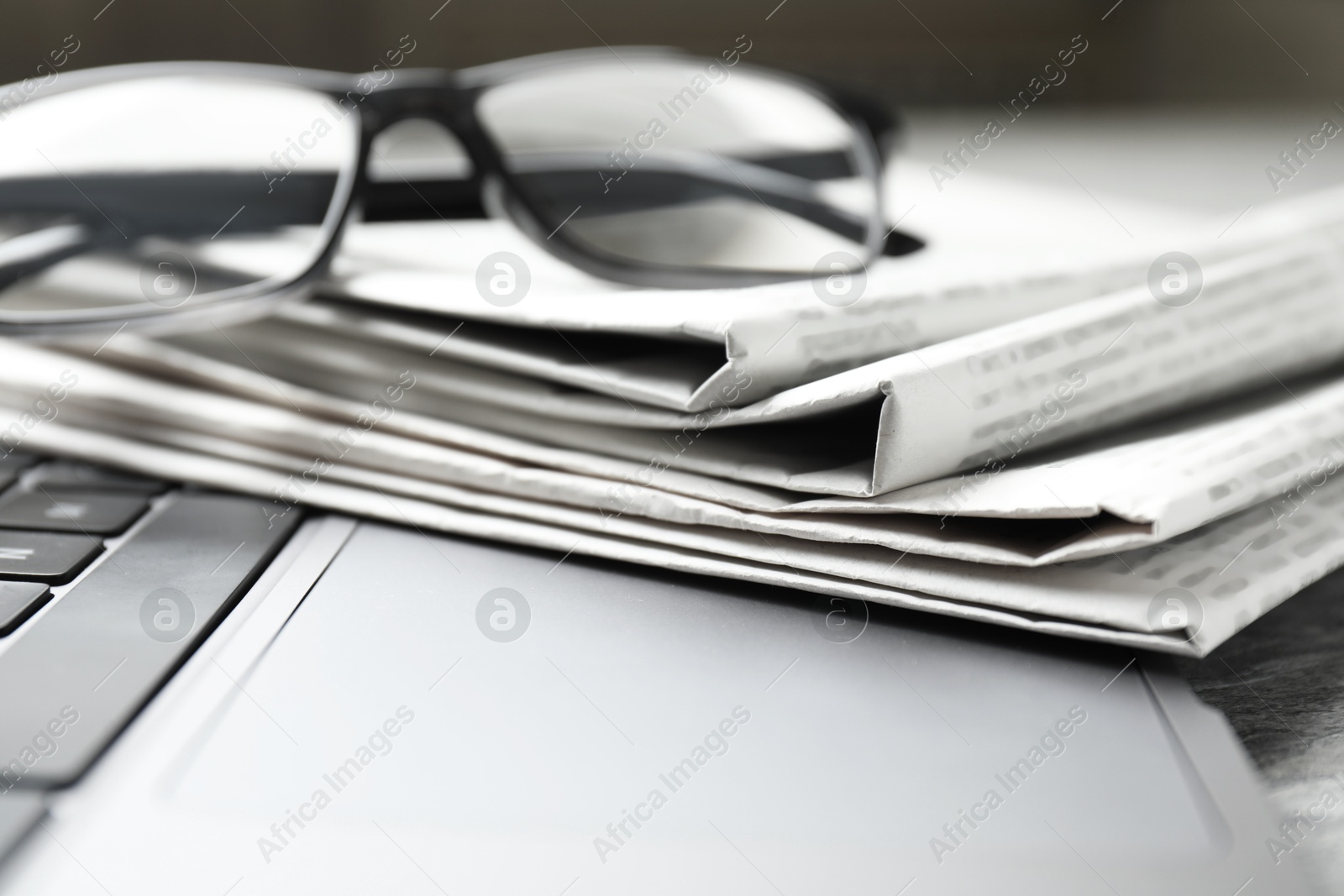 Photo of Newspapers, laptop and glasses on table, closeup