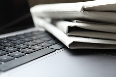 Photo of Stack of newspapers on laptop, closeup view