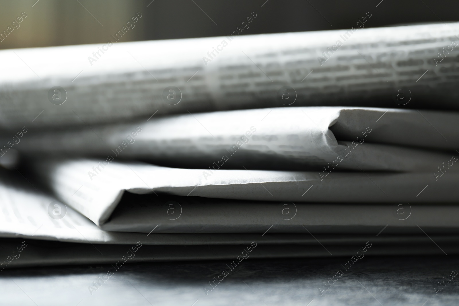 Photo of Stack of newspapers on grey table, closeup