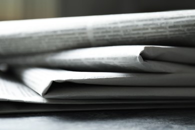 Photo of Stack of newspapers on grey table, closeup