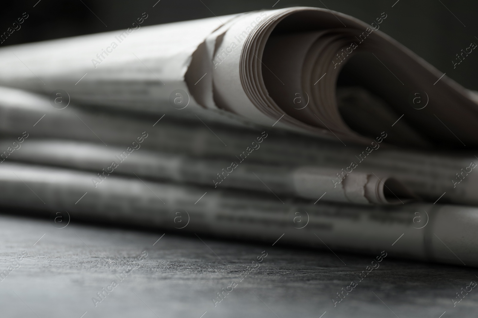 Photo of Stack of newspapers on grey table, closeup