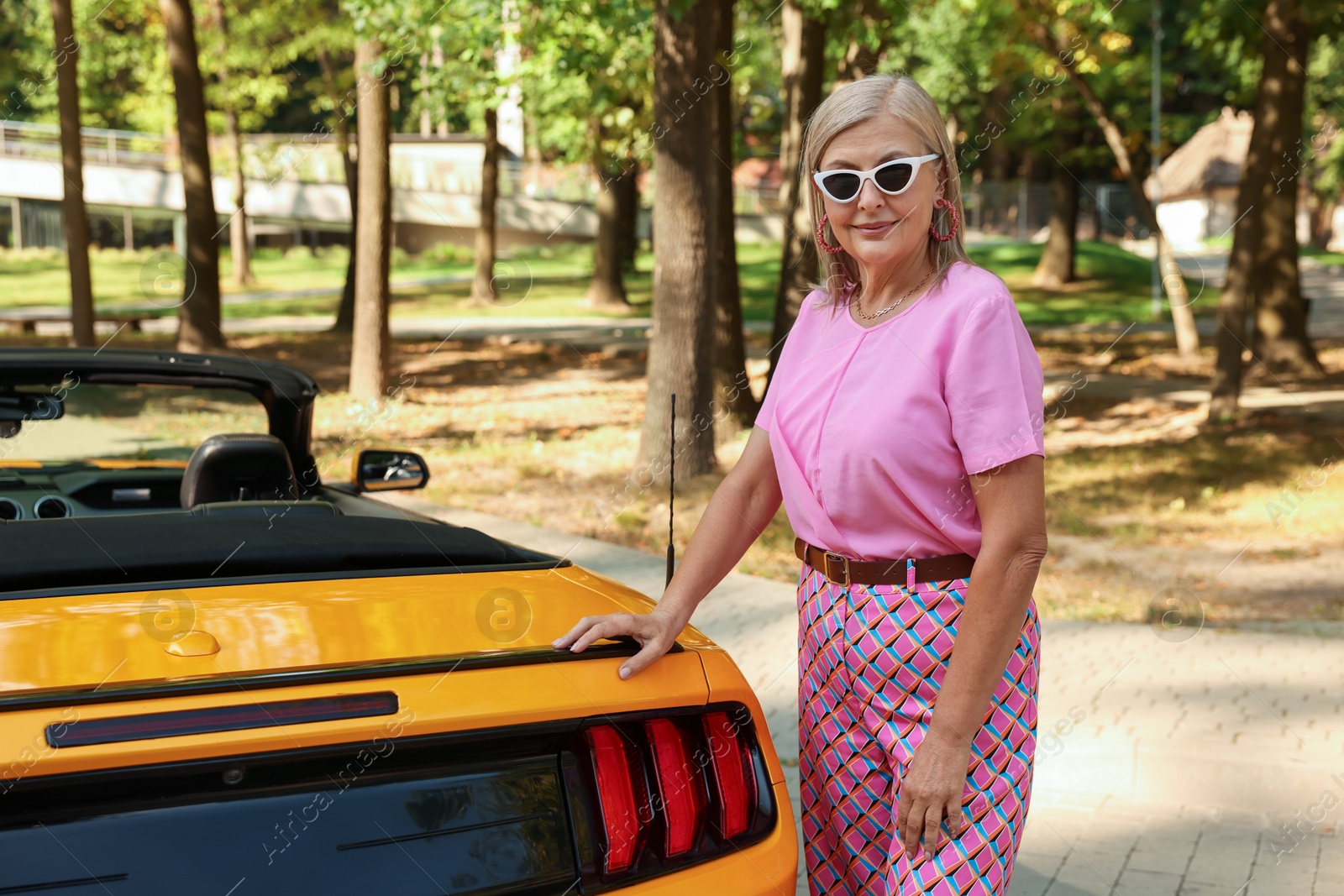 Photo of Stylish senior woman in sunglasses near modern cabriolet outdoors
